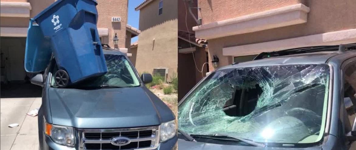 a parked car damaged by wind blown trash can